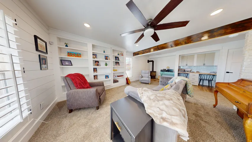 Living area featuring shiplap accent walls, built-in shelving, and carpet flooring