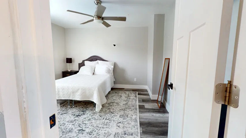 Room featuring light gray walls, wood-finish flooring, a contemporary ceiling fan, and white baseboards