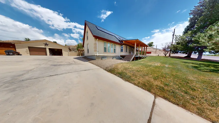 Concrete driveway leading to a two-story residence with an attached covered porch and a detached two-car garage
