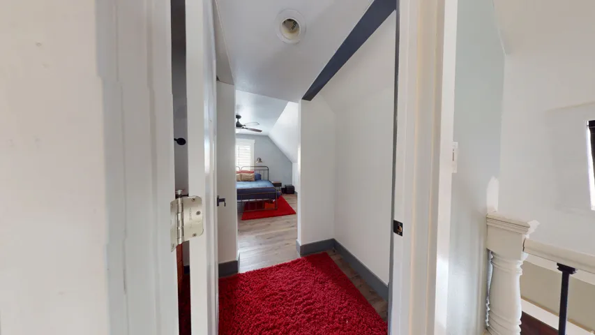 Hallway featuring white walls, dark trim, and wood-finish flooring