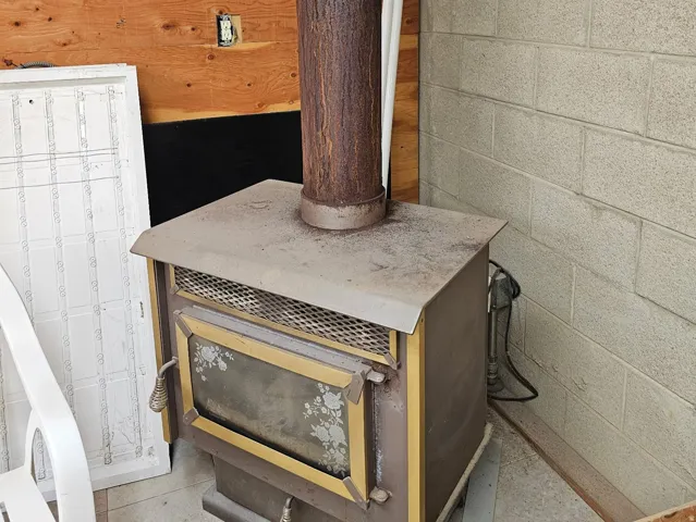Wood-burning stove with a decorative glass door and a textured chimney pipe
