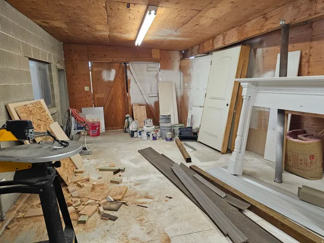 Concrete flooring with exposed wood beam ceiling, featuring a large double-door entry and block wall construction