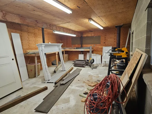 Unfinished room featuring wood paneling, concrete block wall, and exposed wood ceiling