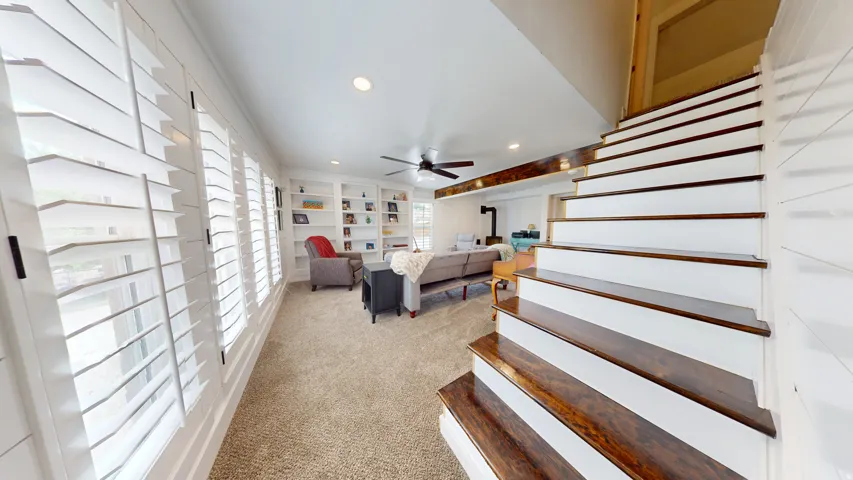 Staircase with wood-finish treads and white risers, framed by shiplap wall paneling