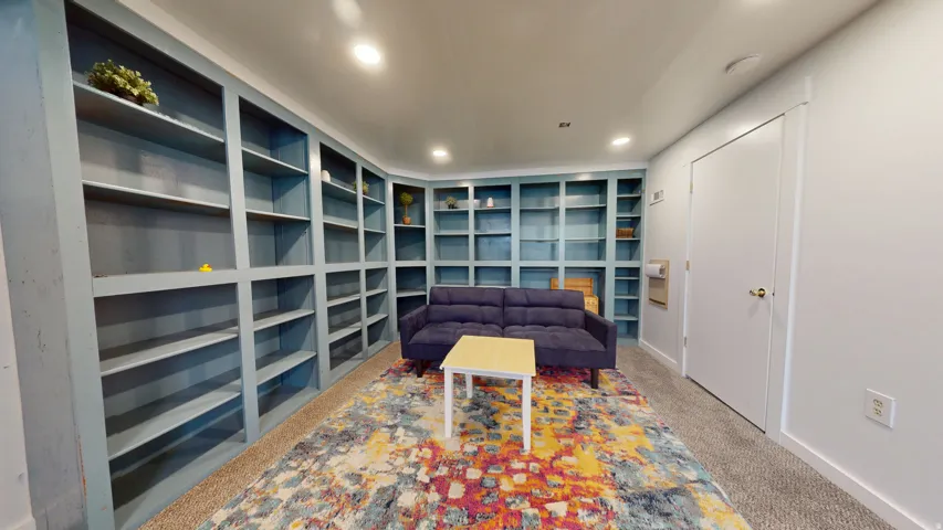 Built-in shelving spanning the wall, recessed lighting, and neutral carpet flooring