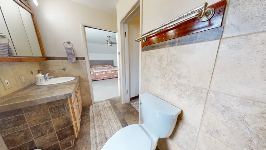 Bathroom featuring a light wood-finish vanity with an integrated sink, a medicine cabinet, tile flooring, and a tiled accent wall