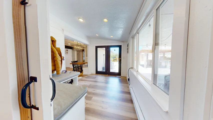 Spacious entry area with wood-finish flooring, recessed lighting, built-in bench seating, and abundant natural light from multiple windows