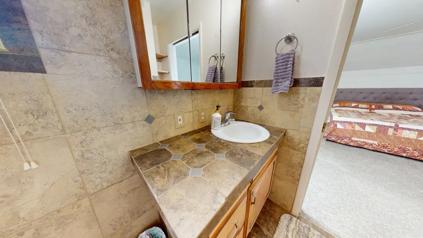 Bathroom vanity featuring a single basin sink, patterned countertop, and wood-finish cabinetry