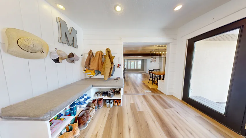 Entryway featuring built-in bench seating with cushion, integrated shoe storage, and wall-mounted coat hooks