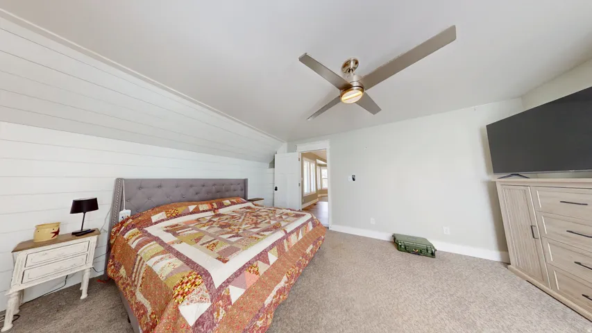 Bedroom featuring a sloped ceiling with white shiplap paneling and a ceiling fan with integrated lighting