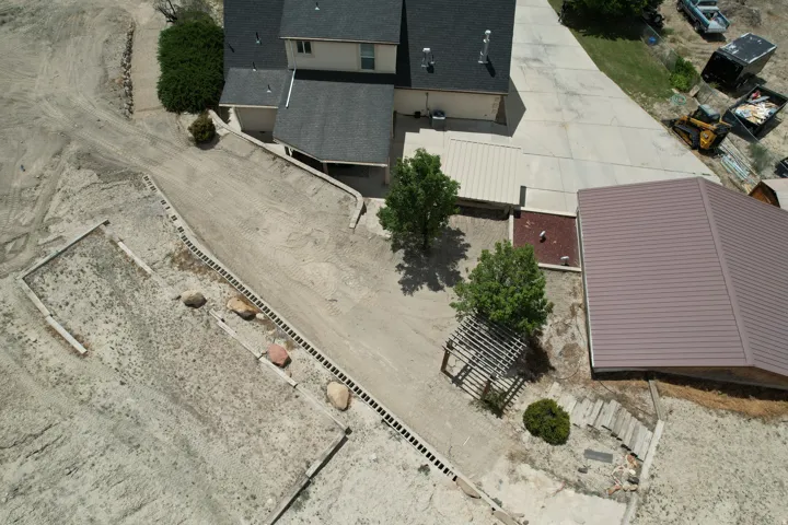 Property exterior featuring a beige stucco facade and dark shingle roof, accompanied by a detached structure with a brown metal roof