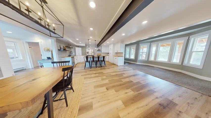 Open-concept living space featuring wood-finish flooring, recessed lighting, and a linear chandelier