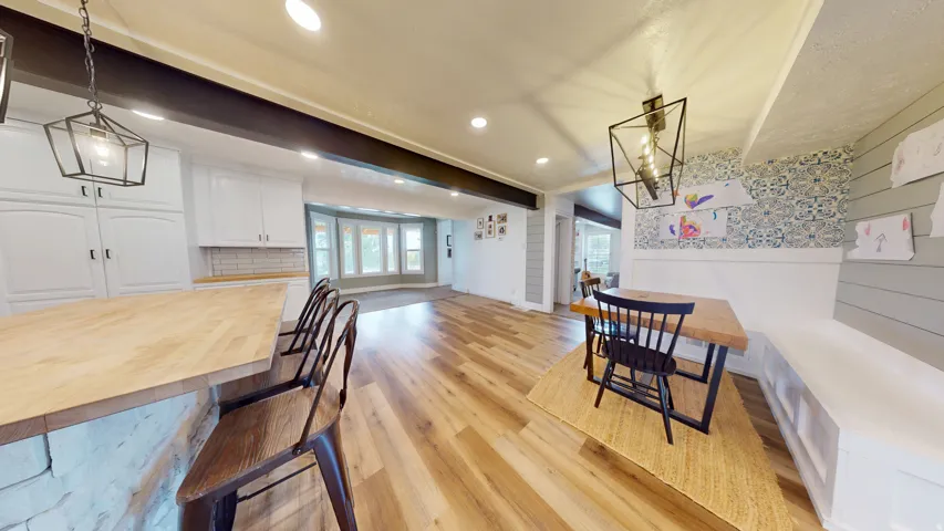 Open-concept living area featuring wood-finish flooring, recessed lighting, and a prominent kitchen island with a stone base and wood countertop