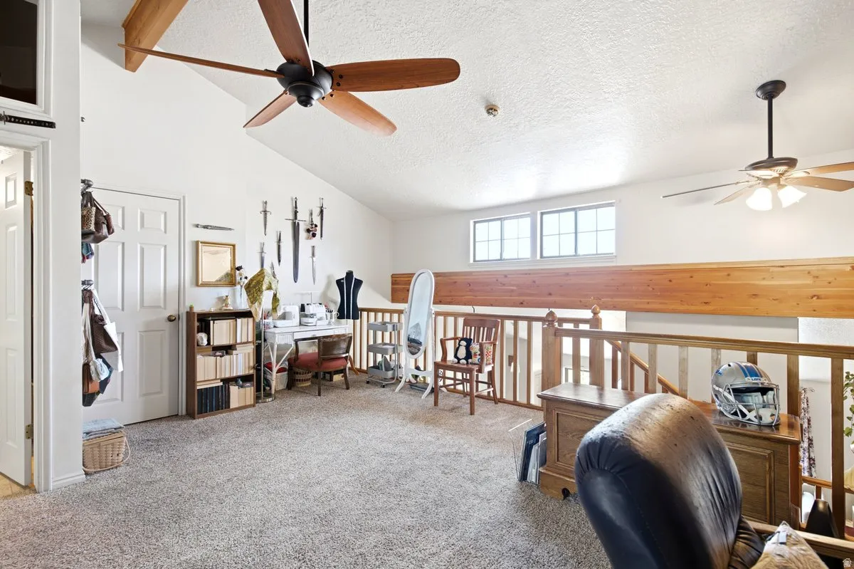 Spacious loft area featuring vaulted ceilings, two ceiling fans, and a light wood railing overlooking the level below