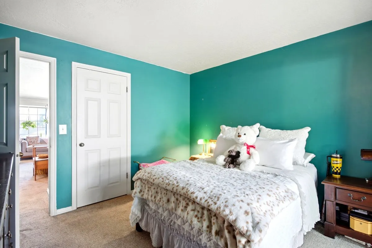 Bedroom featuring teal walls and neutral carpeting