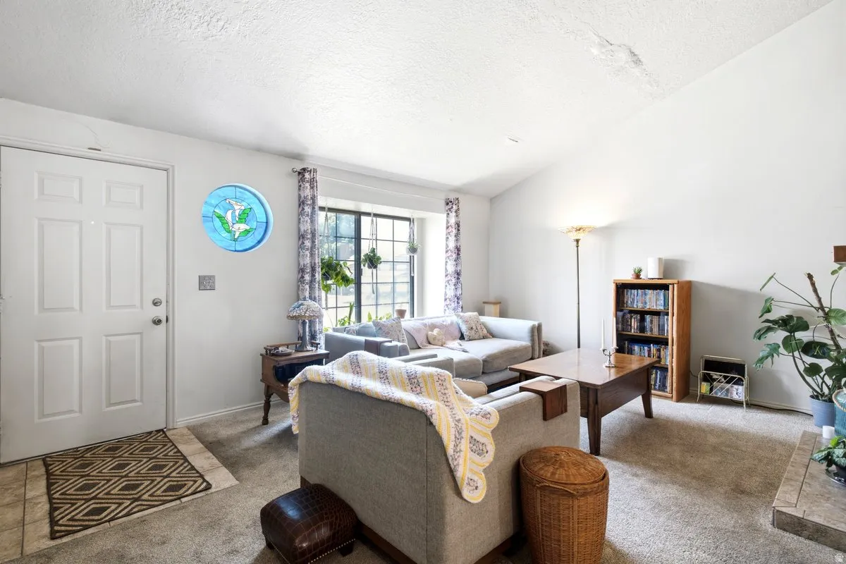 Spacious room featuring vaulted ceilings, a prominent front entry door with panel detailing, and a multi-pane window