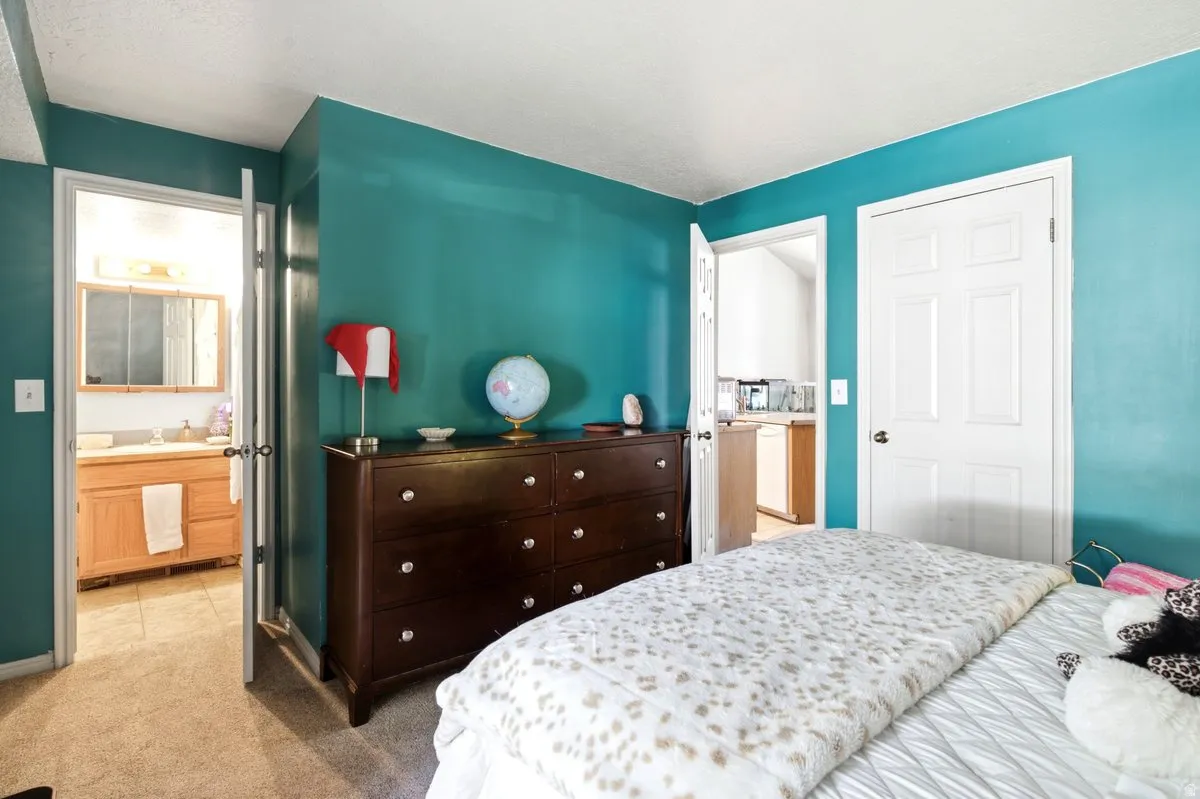 Carpeted room with vibrant teal walls, featuring a dark wood-finish dresser with drawer pulls
