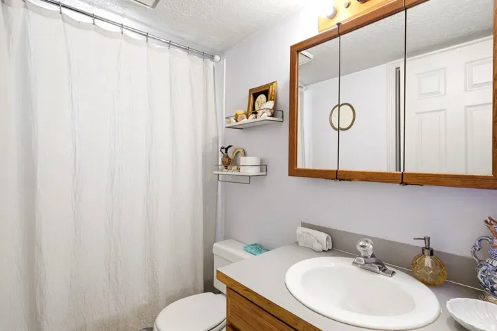 Bathroom featuring a single vanity with an integrated sink, a wood-finish cabinet, and a framed medicine cabinet with overhead lighting