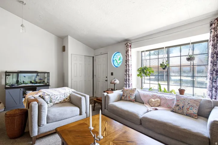 Bright living space featuring a large picture window with grid detailing, vaulted ceiling, and recessed lighting