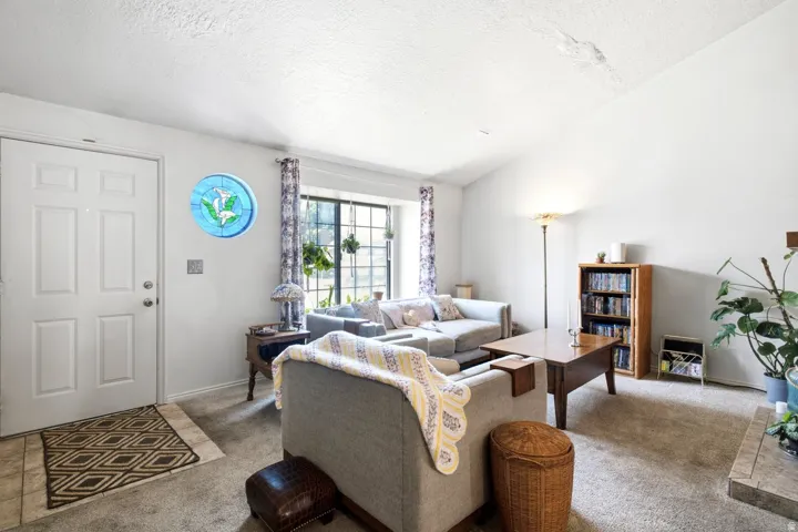 Spacious room featuring vaulted ceilings, a prominent front entry door with panel detailing, and a multi-pane window