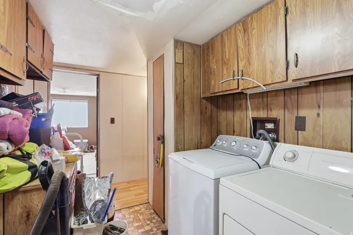 Utility space featuring wood-finish wall paneling, overhead wood-finish cabinetry, and a textured ceiling