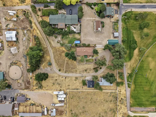 Expansive property featuring multiple structures, unpaved driveways, a round pen, and various mature trees