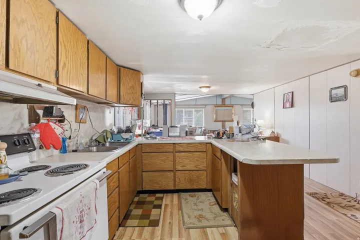 U-shaped kitchen featuring wood-finish cabinetry, white countertops, a built-in oven with electric cooktop, and a kitchen island with seating