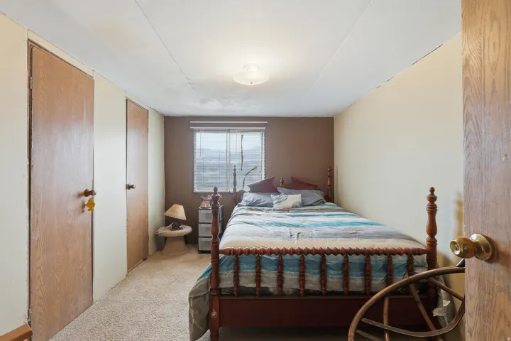 Bedroom featuring light brown carpeting and a single window with horizontal blinds