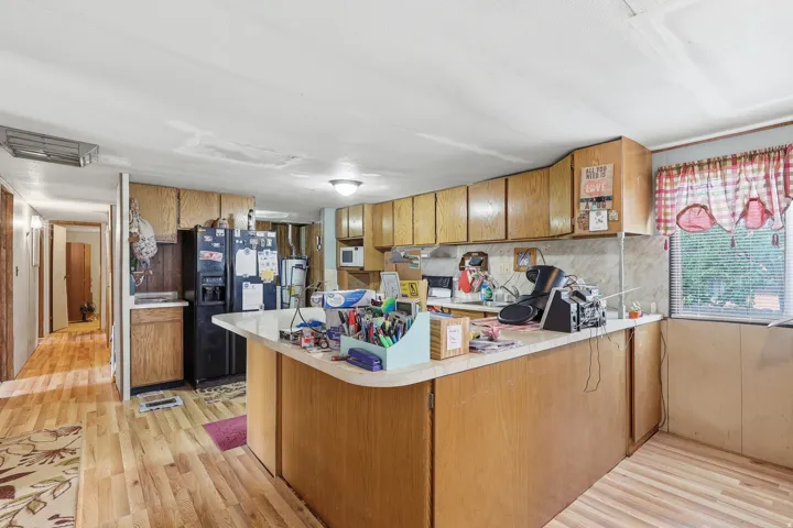 Kitchen featuring wood-finish flooring, wood cabinetry, and a black refrigerator