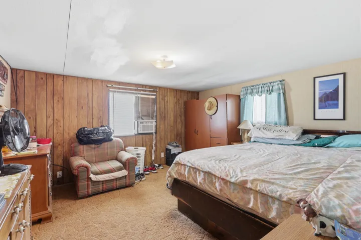 Bedroom featuring wood paneling, a recessed window, and wall-to-wall carpeting