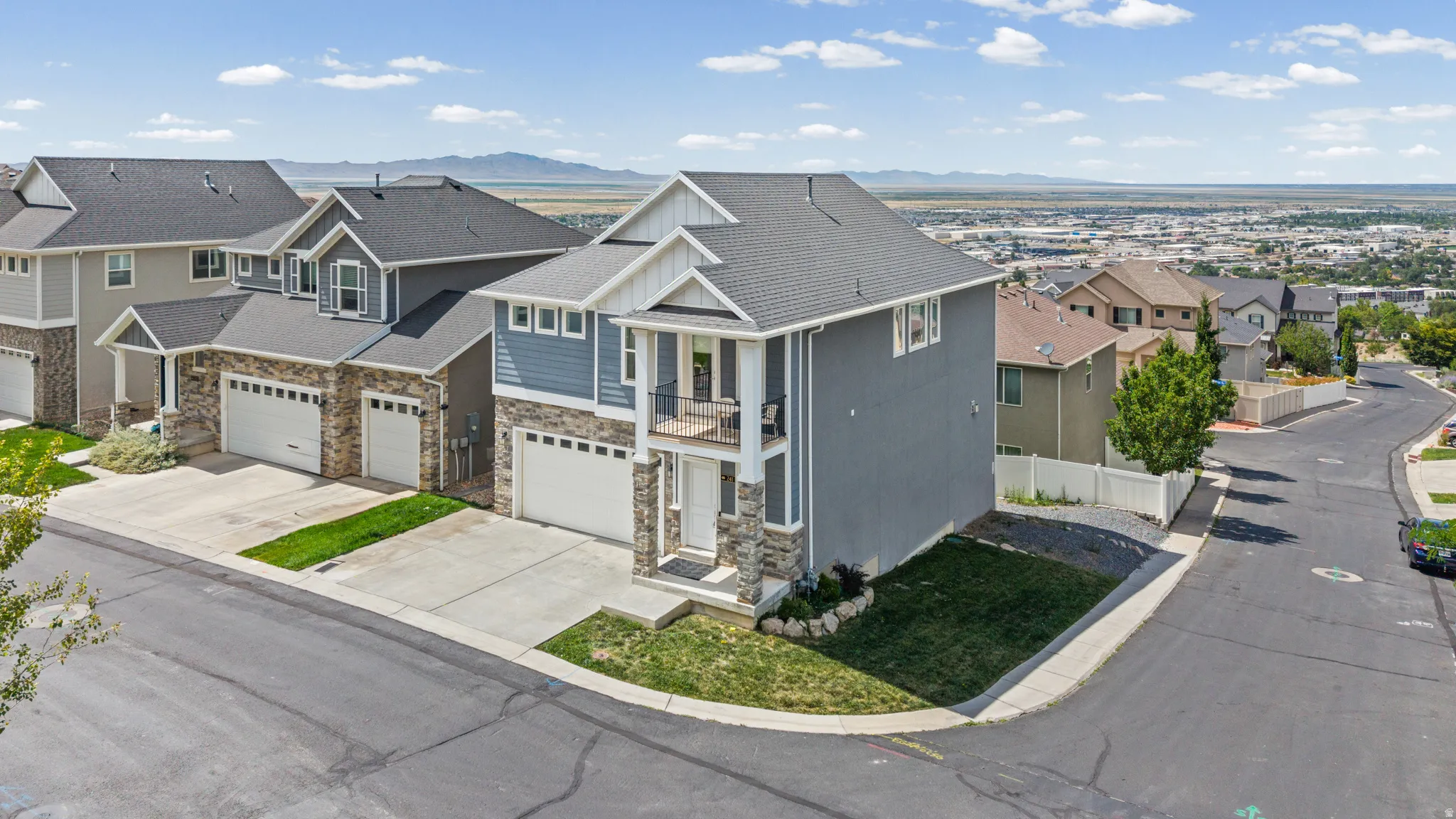 Contemporary two-story residence featuring a light blue and gray exterior with stone accents, a two-car garage, and a second-story balcony