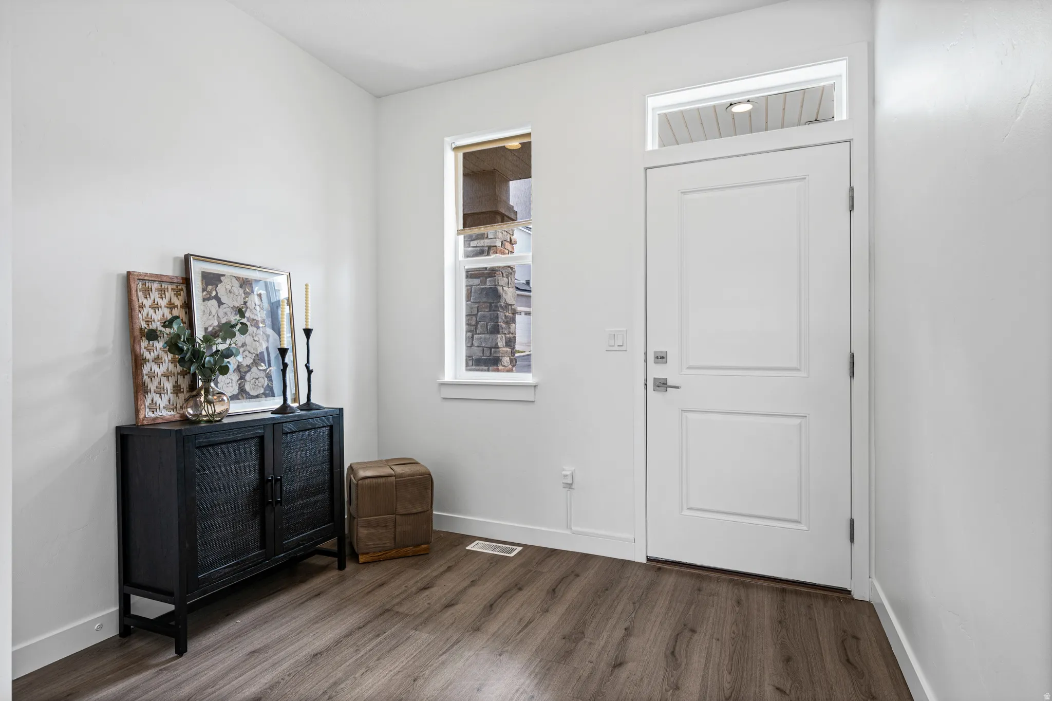 Entryway featuring a white paneled door with a transom window, wood-finish flooring, and white baseboards
