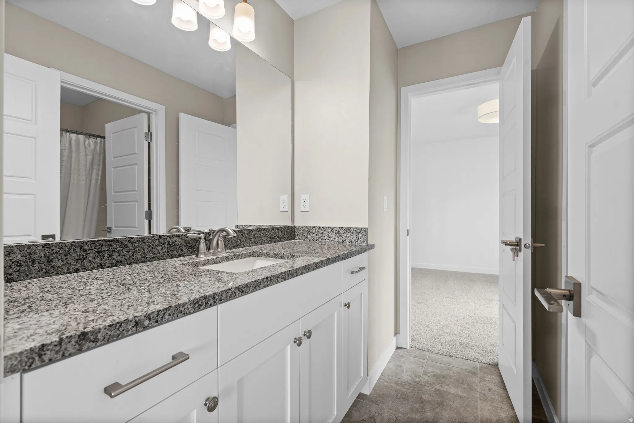 Spacious bathroom featuring a double vanity with granite countertops, undermount sinks, and contemporary brushed nickel hardware