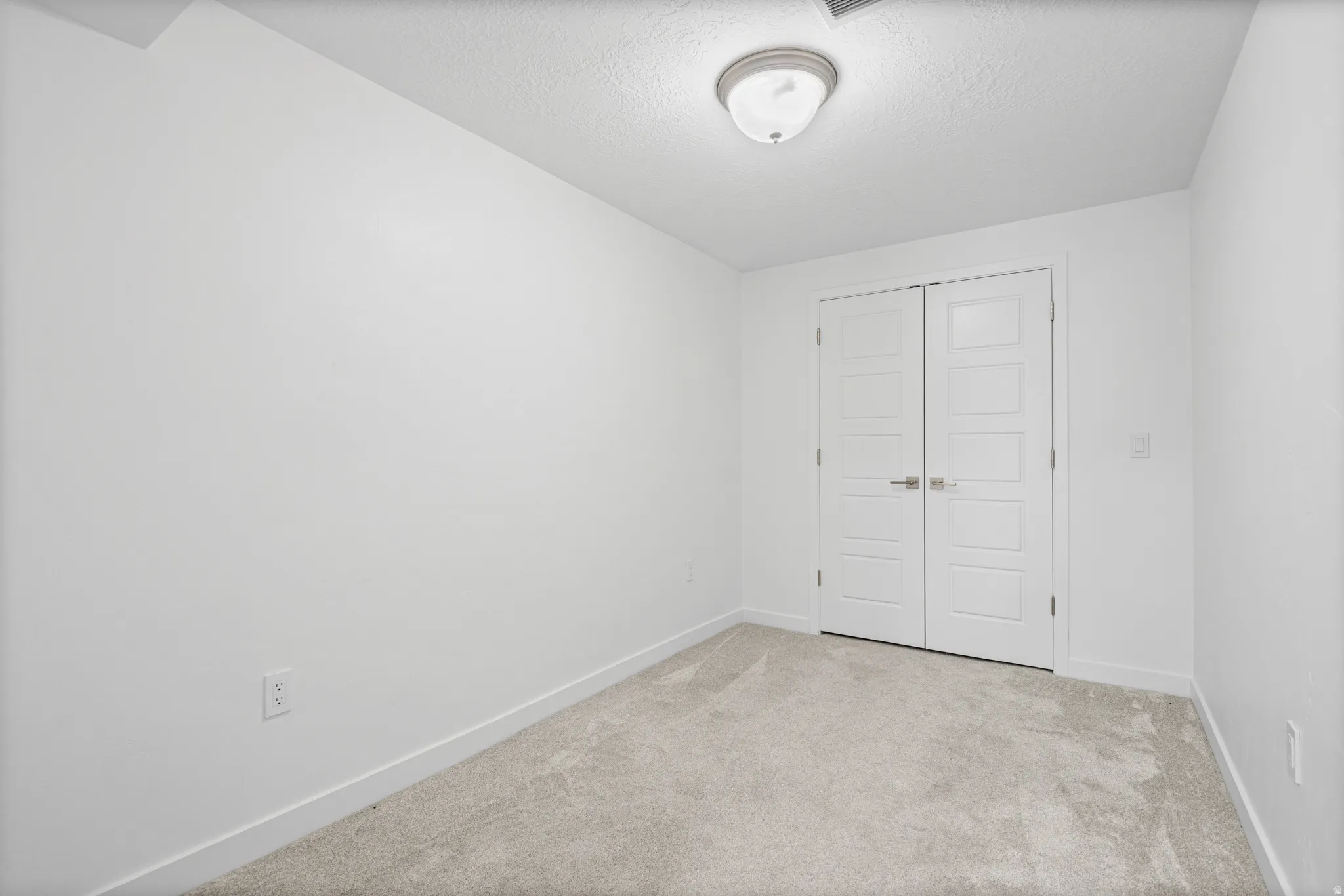 Light gray carpeted room featuring white walls and a white ceiling