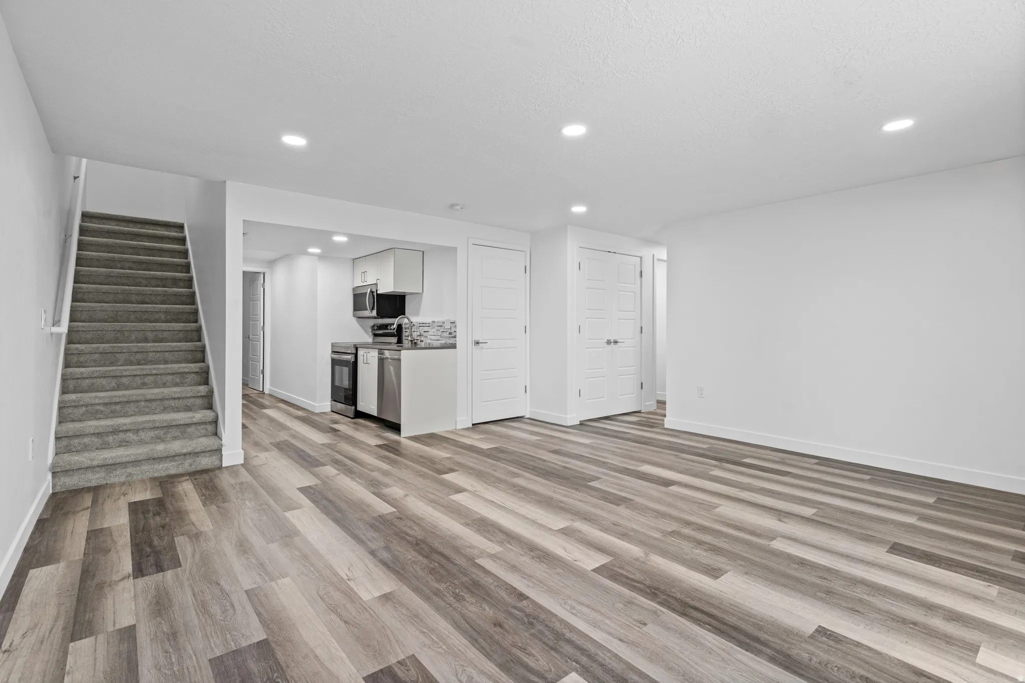 Spacious living area featuring wood-finish flooring, recessed lighting, and a neutral color palette