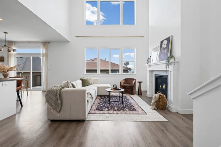 Living area featuring high ceilings with upper windows, a fireplace with a white mantel and tiled surround, and wood-finish flooring