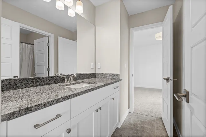 Spacious bathroom featuring a double vanity with granite countertops, undermount sinks, and contemporary brushed nickel hardware