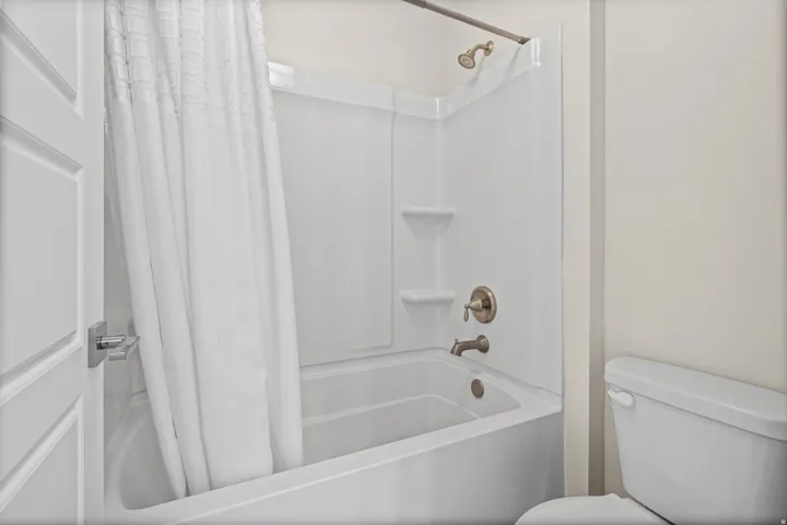 Bathtub and shower combination featuring brushed nickel fixtures and integrated shelving