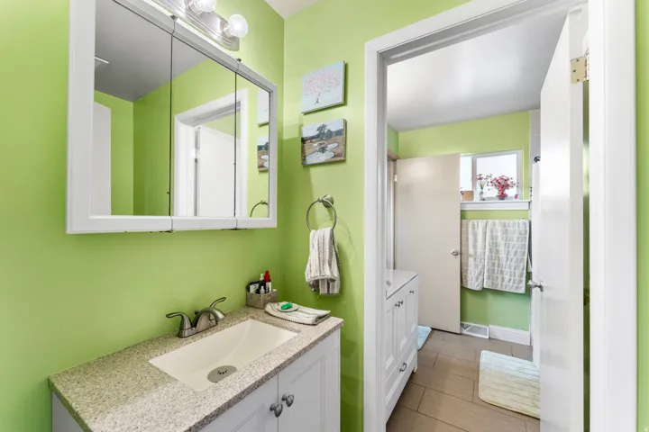 Bathroom vanity featuring a light-toned solid surface countertop with an integrated rectangular sink