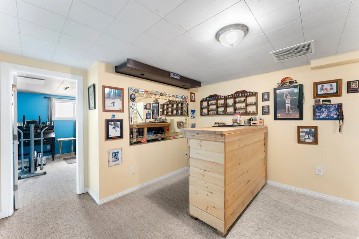Recreation room featuring a wood-panel accent wall, built-in shelving, plush carpet, and a drop ceiling with recessed lighting