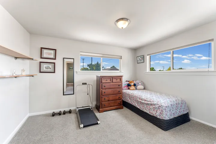 Light-filled room featuring multiple windows, recessed ceiling light, wall-mounted shelving, and neutral carpeting