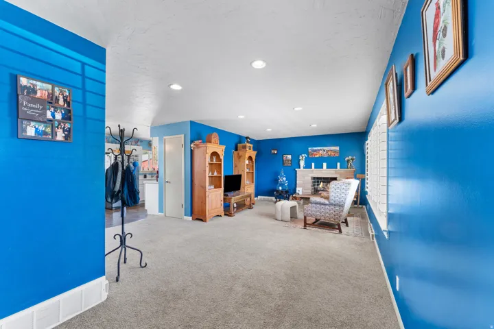 Open concept living space featuring recessed lighting, a fireplace with a tile surround and mantel, and carpet flooring