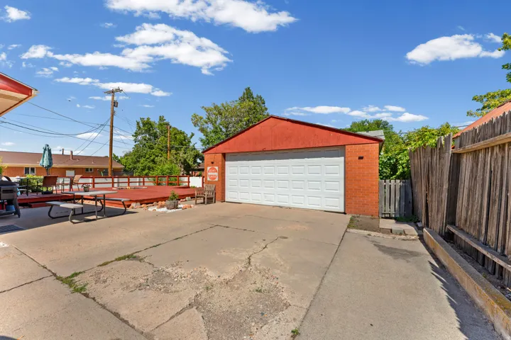 Detached brick garage with a white sectional door and red roof