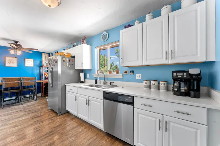 Kitchen featuring white cabinetry with silver-tone hardware, wood-finish flooring, and a dining area with a ceiling fan