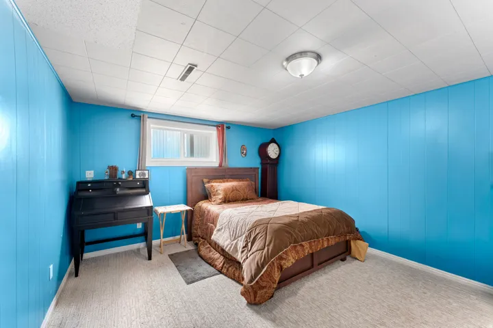 Spacious room featuring light blue paneled walls, white acoustic tile ceiling, and light-colored carpet flooring