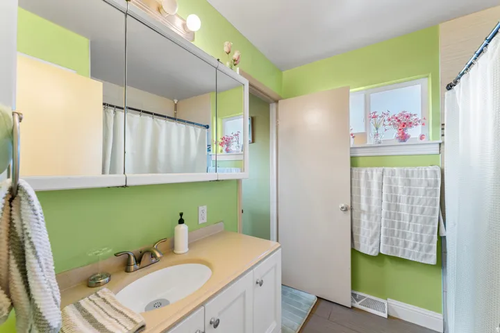 Bathroom vanity featuring a built-in sink, brushed nickel faucet, and white cabinetry
