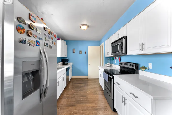 Galley kitchen featuring wood-finish flooring and bright blue walls