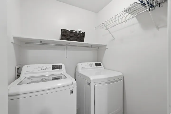 Dedicated laundry area featuring white walls and a white wire shelving unit for organization