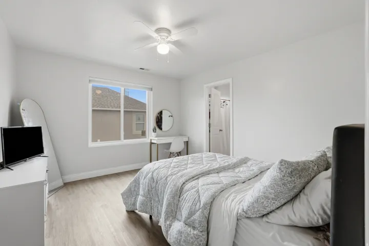 Bedroom featuring wood-finish flooring, a ceiling fan with integrated lighting, a rectangular window, and a closet with a white door