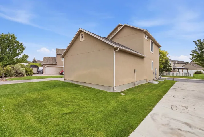 Stucco exterior with a gable roofline, featuring a manicured lawn and a concrete driveway